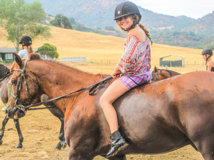 A camper riding bareback on a horse.