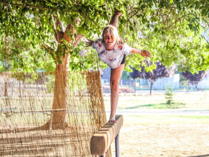 A camper practicing her gymnastics skills on the balance beam.