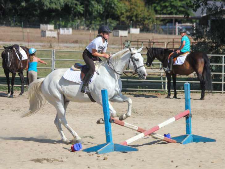 A camper jumping across an obstacle on horseback.