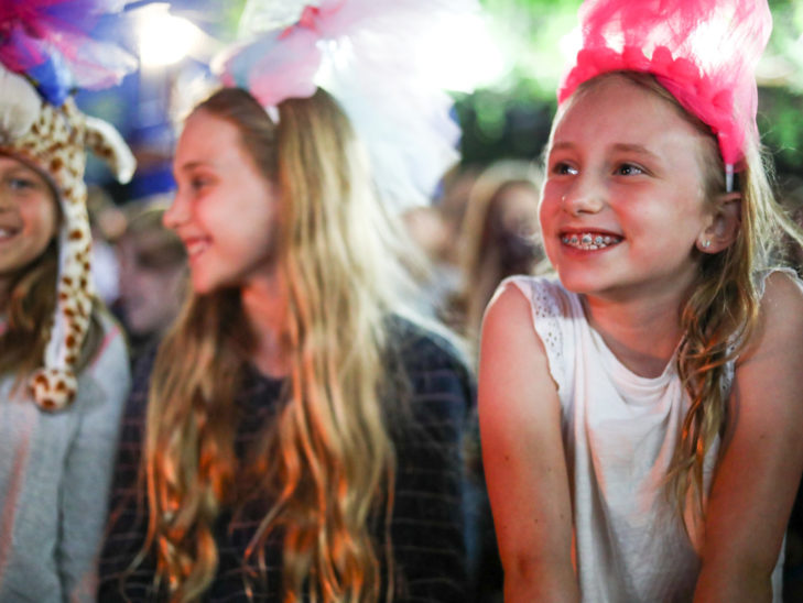 A camper smiling while watching improv.