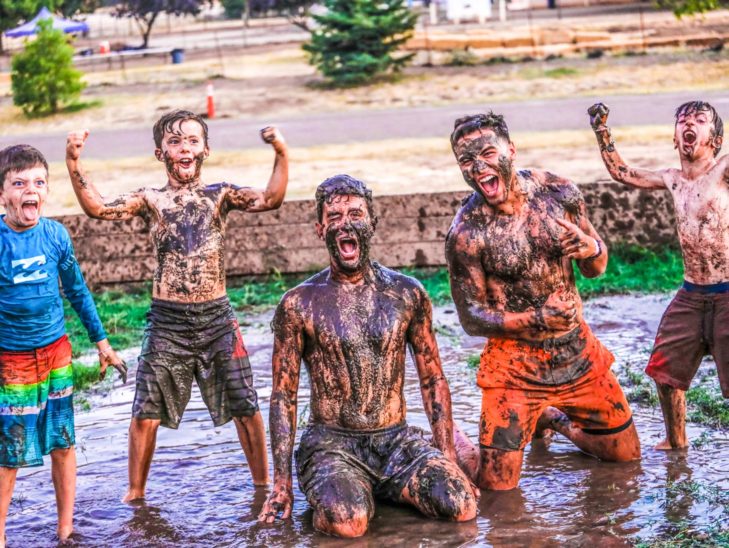 Campers yelling with their hands in the air in the mud during a game of gaga.