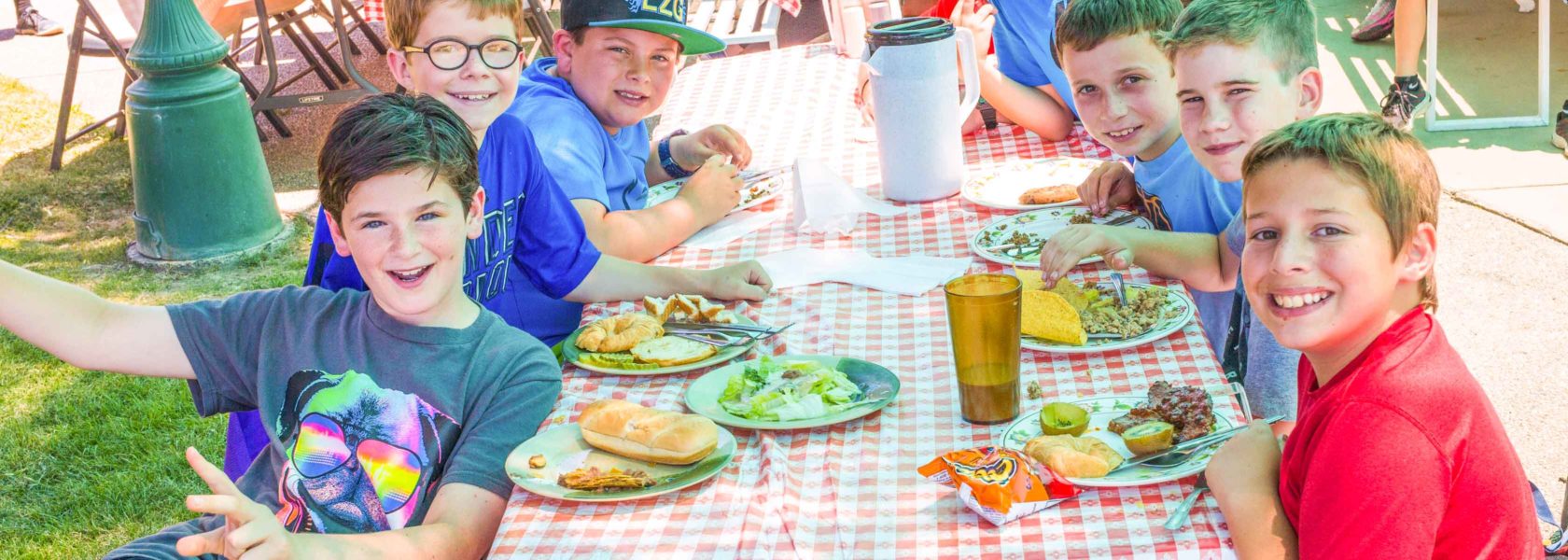 Campers sitting at a picnic table eating food.