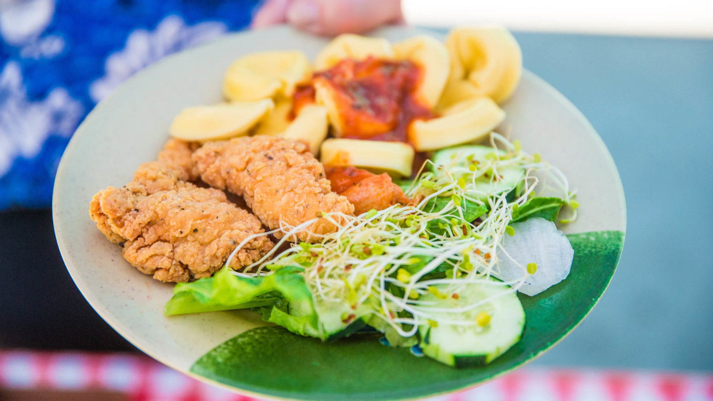 Chicken tenders, a salad, and tortellini on a plate.