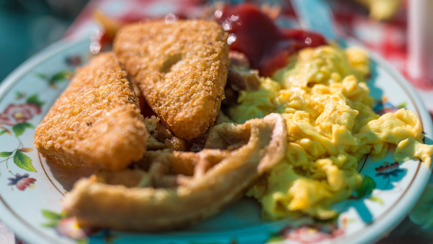 Waffles, eggs, and hash browns on a plate.