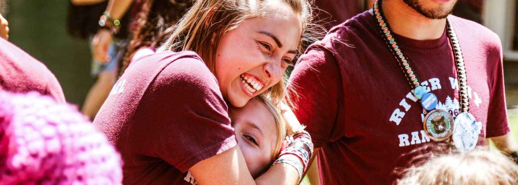 A counselor hugging a camper and smiling.