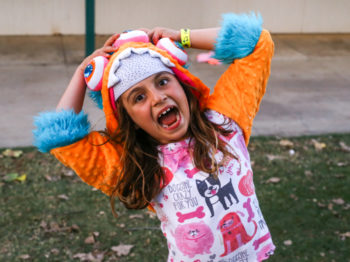 A camper smiling and laughing at the camera while dressed in colorful clothes.