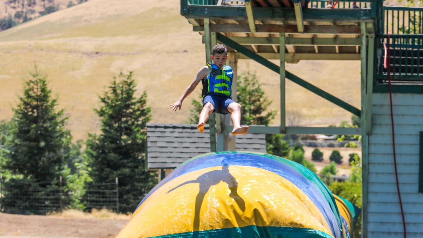 A camper jumping on an inflatable bouncy trampoline