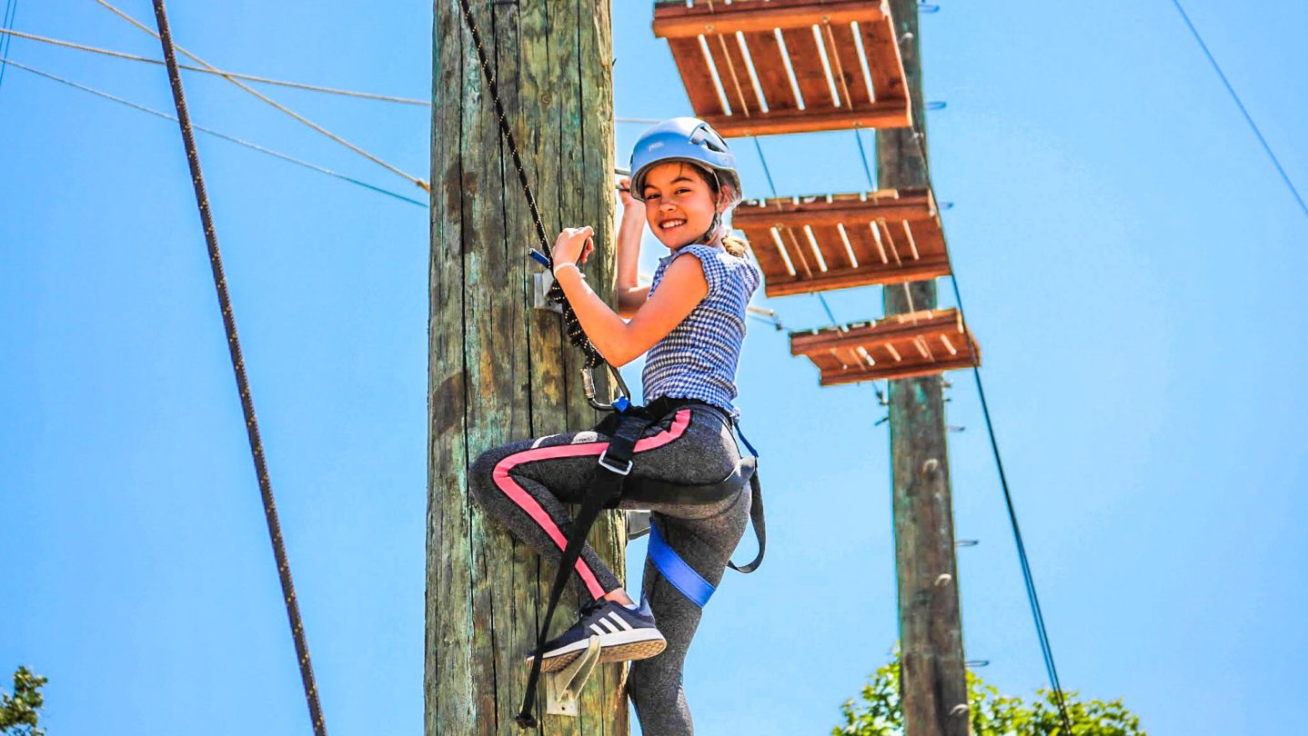 A camper climbing a ropes course