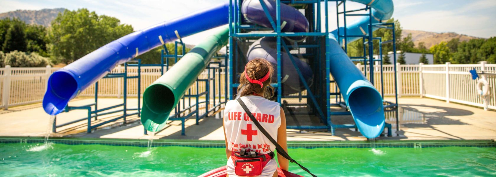 A lifeguard standing by the pool and water slide.