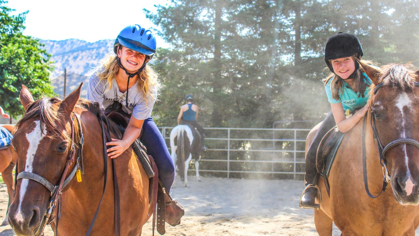 Campers smiling while riding horses