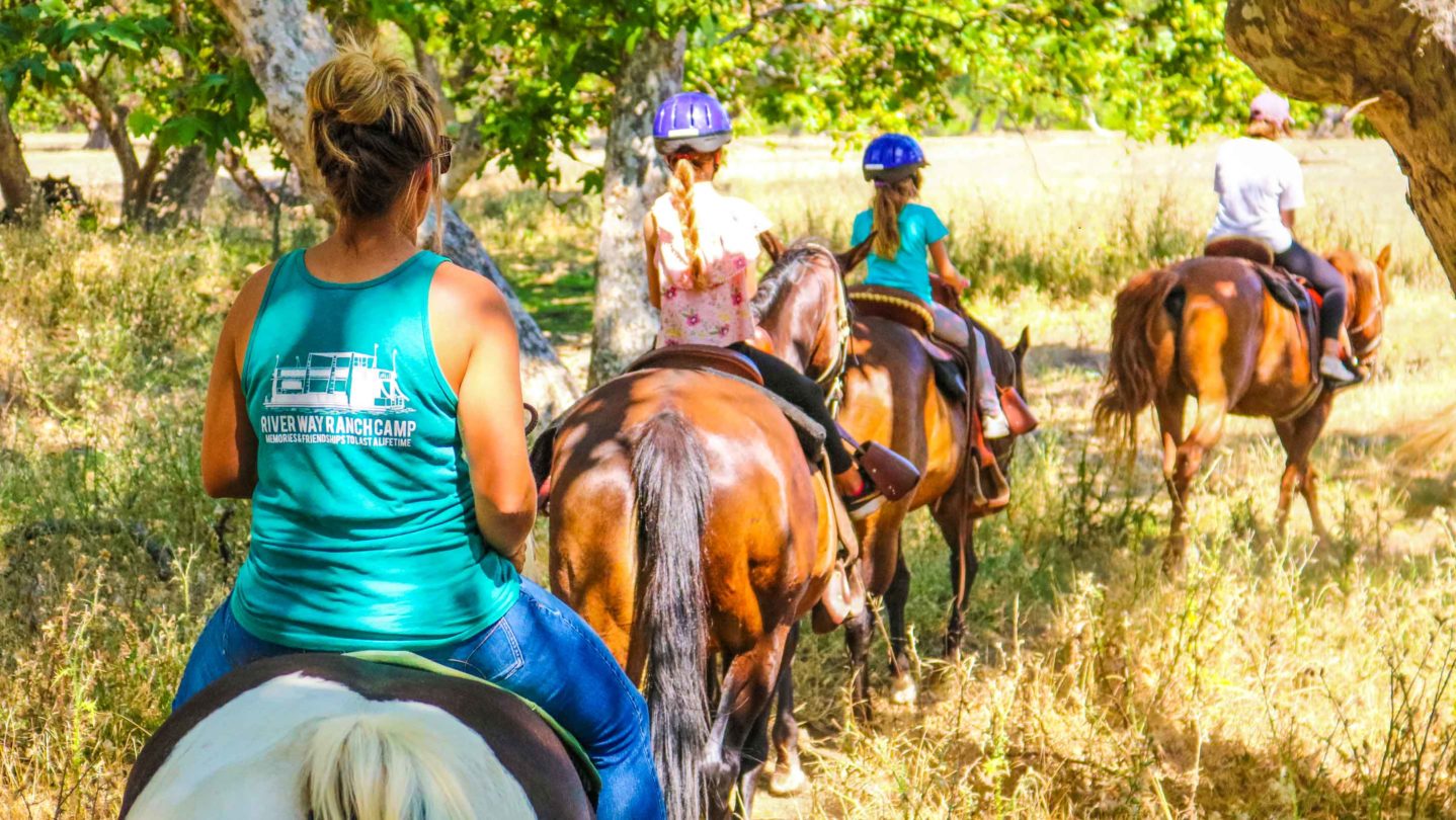 Campers riding horses on a trail