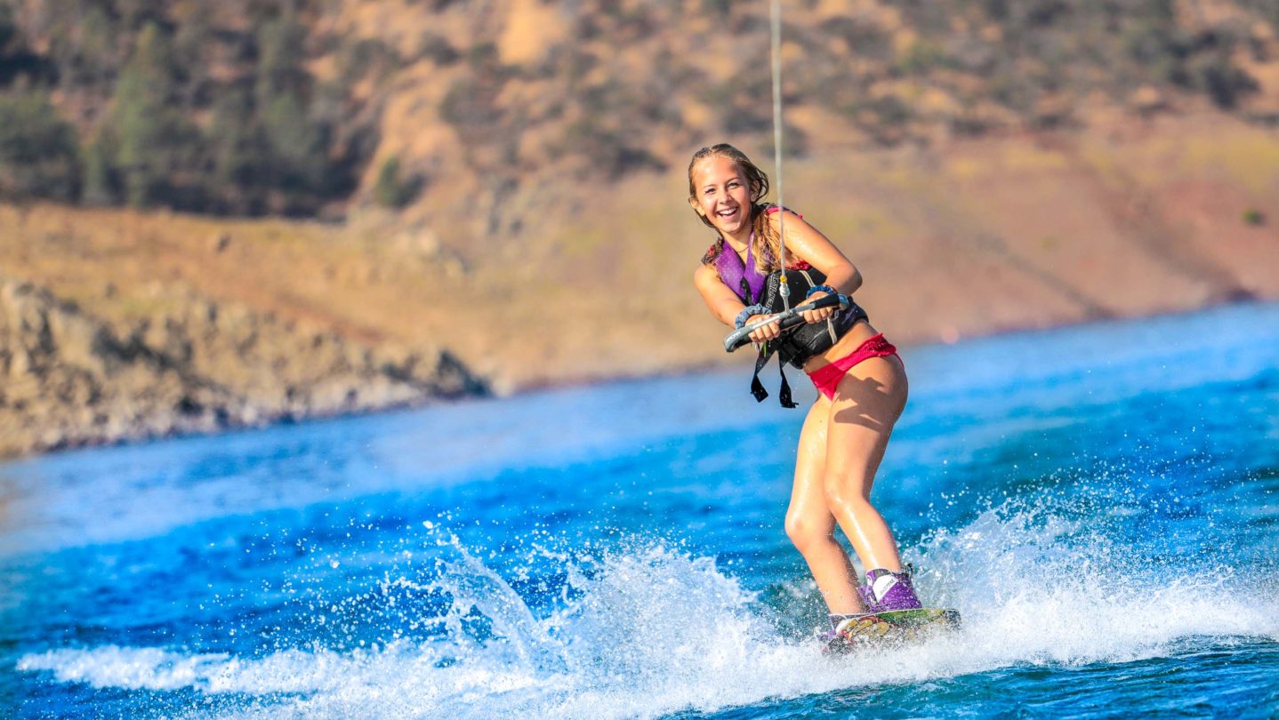 A camper learning how to waterski and smiling