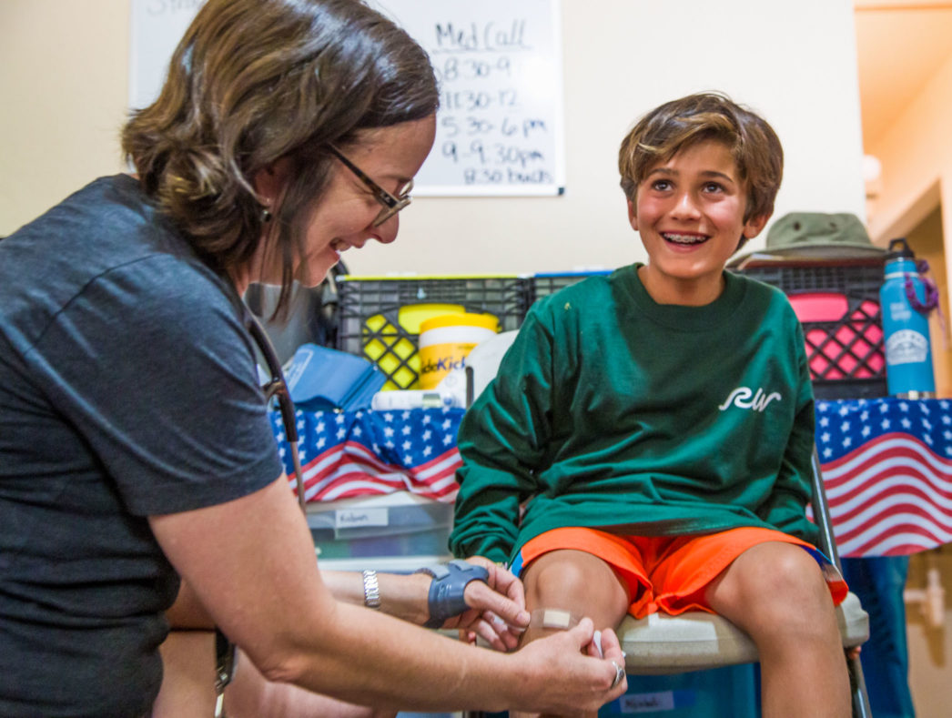 A camper getting a bandaid put on his knee.