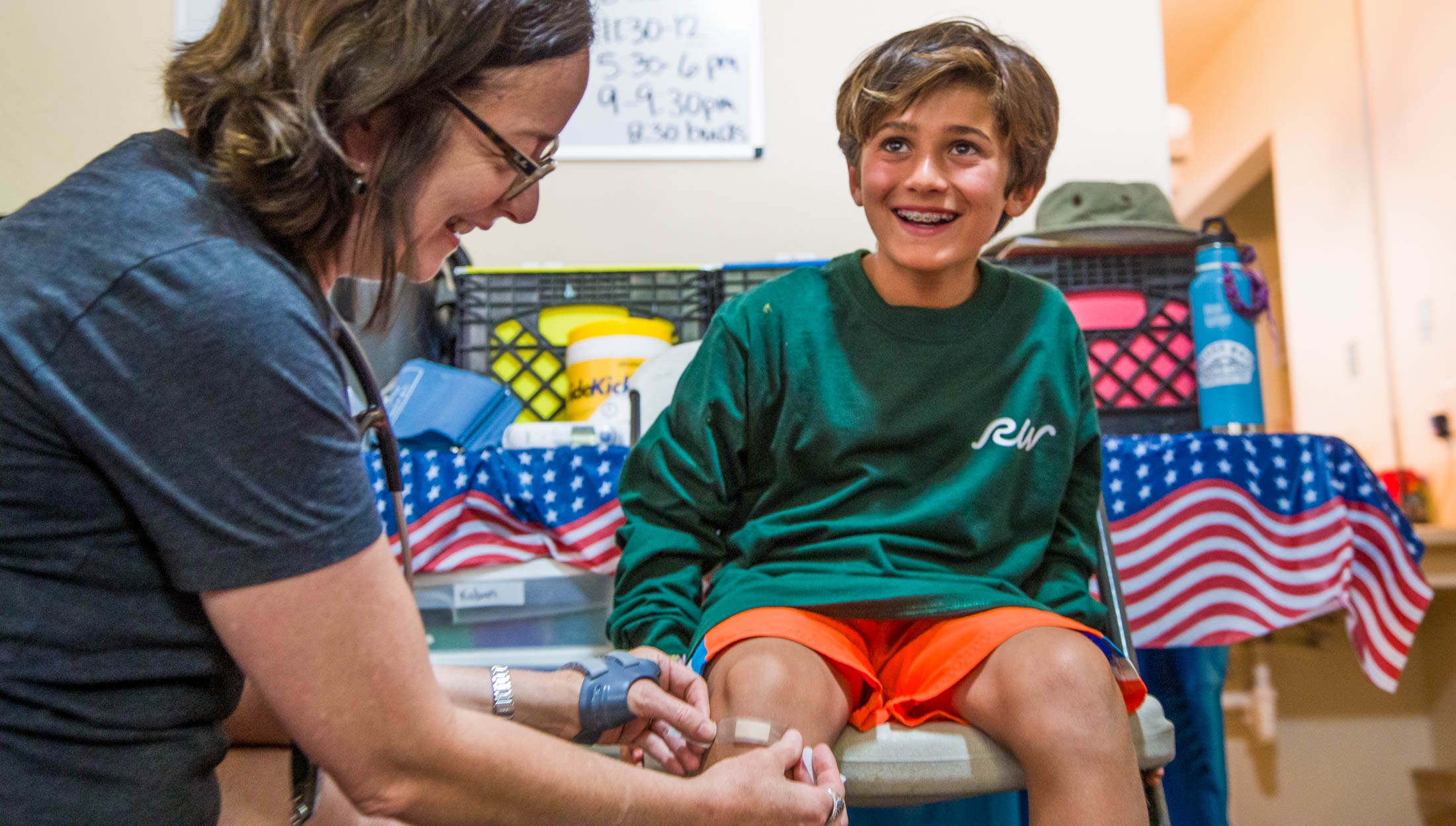 A camper getting a bandaid put on his knee.